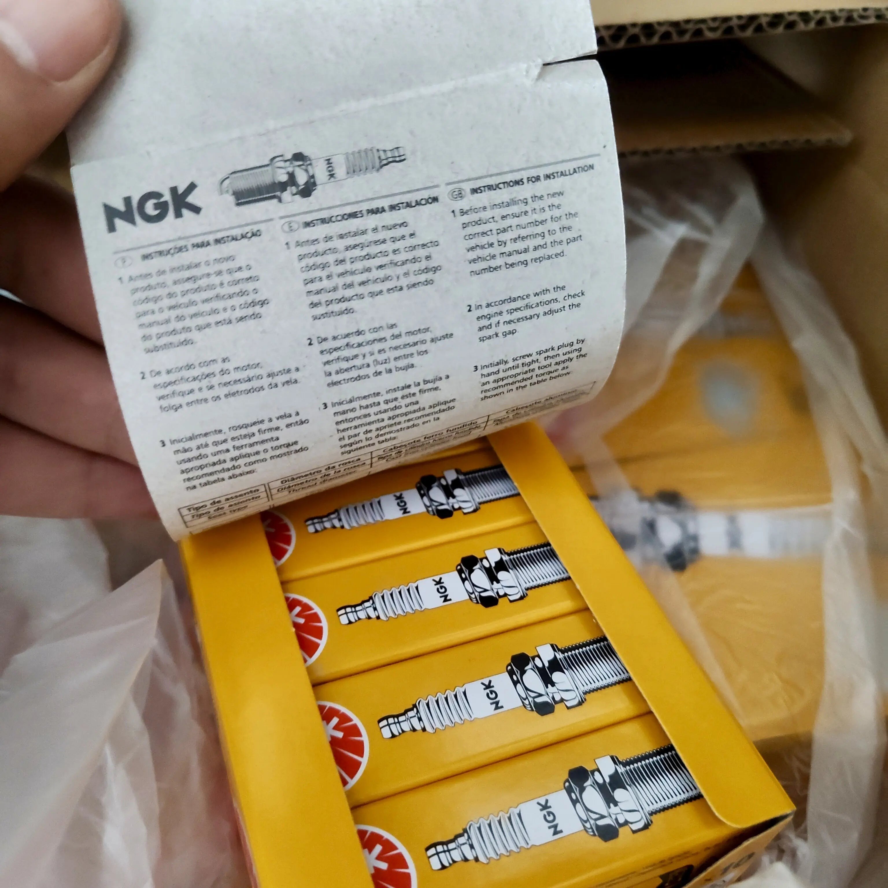 BANQIU Cambodia Co.,Ltd. 提供的高性能 NGK 火花塞，包装在黄色纸盒中，附带安装说明书。